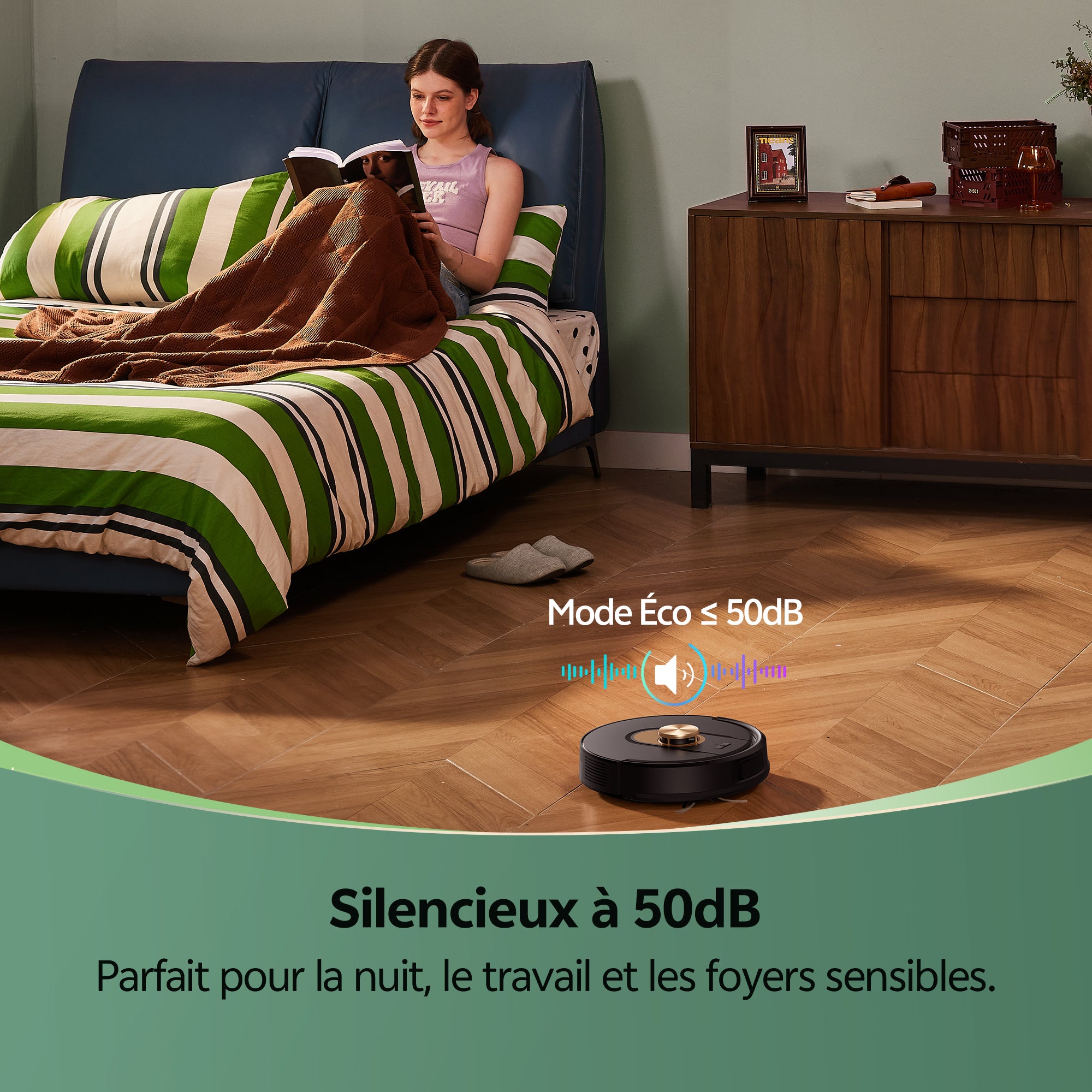 Woman reading in bed with a robot vacuum cleaner on the floor, emphasizing eco mode and noise level.
